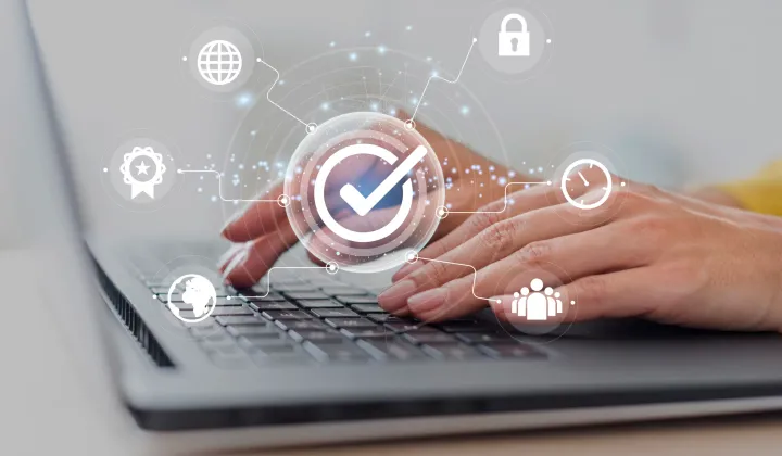 Person using laptop with digital security icons overlay.