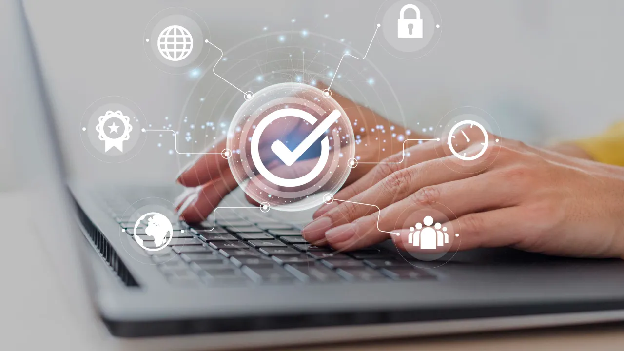 Person using laptop with digital security icons overlay.